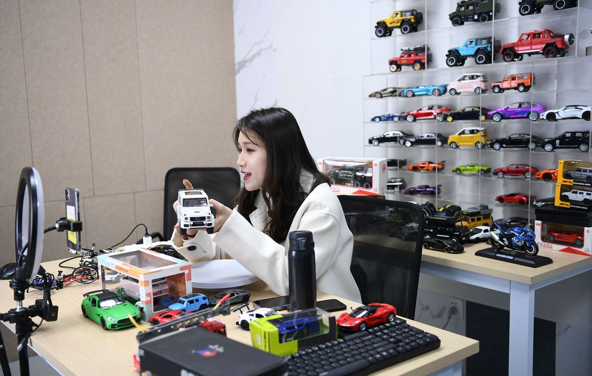 (211202) -- SHANTOU, Dec. 2, 2021 (Xinhua) -- A social media influencer promotes toys via livestreaming in Chenghai District of Shantou City, south China's Guangdong Province, Dec. 2, 2021. Chenghai District in the city of Shantou is dubbed "the capital of toys in China" as the toy industry continues to flourish in this coastal region and a complete industrial chain has been formed.  To overcome the impact of the COVID-19 outbreak on the toy industry, the local authorities have been actively supporting the upgrading of the toy industry and helping enterprises build sales platforms as well as open up new sales channels.   In the first three quarters of 2021, the toy production value of Chenghai hit 9.296 billion yuan (about 1.4 billion U.S. dollars) and from January to July this year, the district has exported toys worth 2.738 billion yuan, accounting for 56.64 percent of the district's total exports. (Xinhua/Deng Hua) (Photo by Deng Hua / XINHUA / Xinhua via AFP)