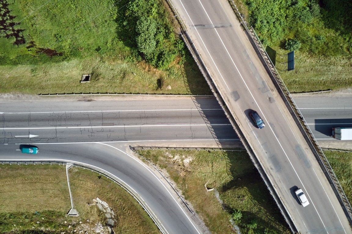 Aerial view of road intersection with fast moving heavy traffic on city streets. Uban transportation during rush hour with many cars and trucks