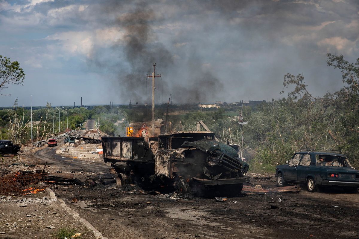 1241009513 LYSYCHANSK, LUHANSK OBLAST, UKRAINE - 2022/05/28: A destroyed truck can be seen on fire near the bridge connecting Severodoonetsk and Lysychansk, Luhansk. As Russian troops launching the offensive from multiple directions, hoping to cut off Ukrainian supplies and reinforcements and gain full control of the Luhansk Oblast, the town of Lysychansk connecting Severodoonetsk is heavily bombarded and sieged. (Photo by Alex Chan Tsz Yuk/SOPA Images/LightRocket via Getty Images)