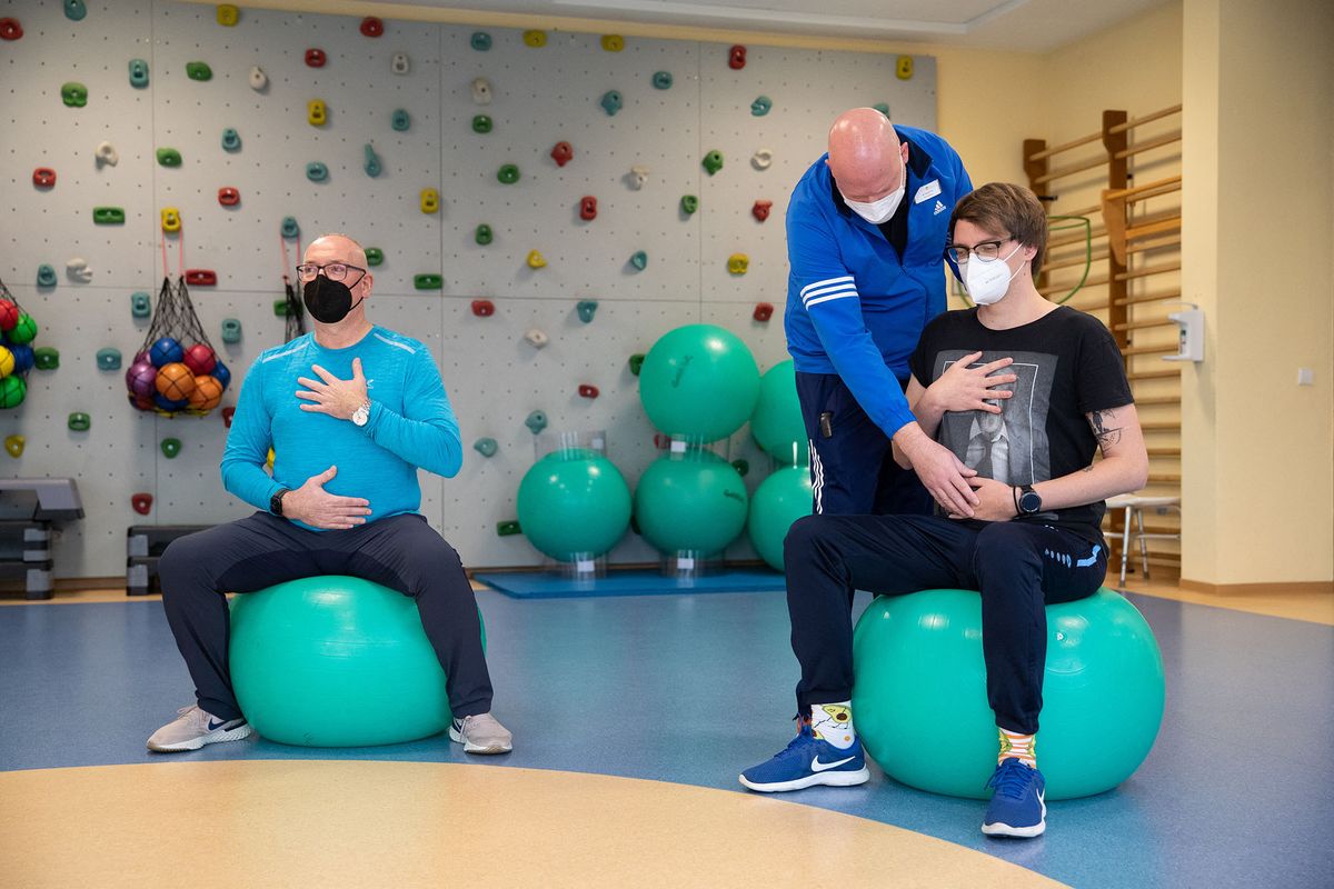 21 January 2022, Lower Saxony, Bad Rothenfelde: Long-covid patients Jˆrg Schneider (l) and Ulrich Lowers (r) do breathing training with physiotherapist Mirko Weernink (m) in a gymnastics room at the Teutoburger Wald Clinic, a rehabilitation clinic for post-covid patients. Lower Saxony's Health Minister Behrens (SPD) visits the facility. Photo: Friso Gentsch/dpa (Photo by FRISO GENTSCH / DPA / dpa Picture-Alliance via AFP)