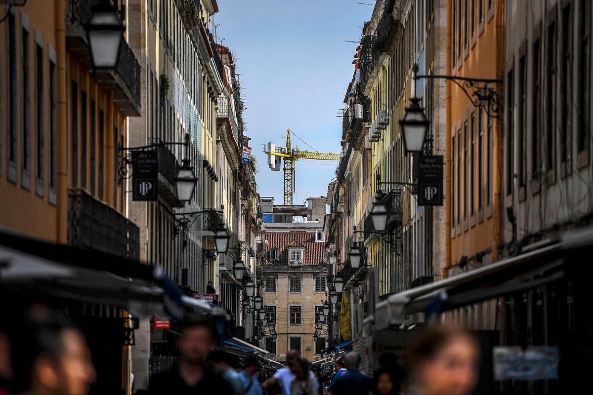 A construction crane rises at the end of Correeiros Street in downtown Lisbon on April 19, 2018. - Lisbon's azure skies are dotted with forests of cranes as scores of construction workers give Portugal's capital a shiny and new, if pricey, veneer. For years the local construction industry lay in the doldrums -- but those days are gone with the city today a hive of activity, a boon for those involved in its overhaul. (Photo by PATRICIA DE MELO MOREIRA / AFP)