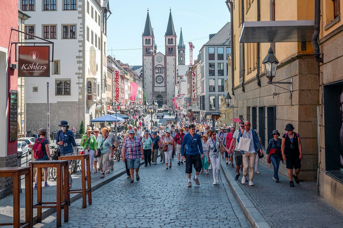 11 May 2022, Bavaria, W¸rzburg: Tourist groups are guided across the Old Main Bridge from the city center. W¸rzburg Cathedral can be seen in the background. Sunny weather and early summer temperatures in W¸rzburg. According to the DWD, up to 29 degrees are expected in W¸rzburg. Photo: Daniel Vogl/dpa (Photo by Daniel Vogl / DPA / dpa Picture-Alliance via AFP)