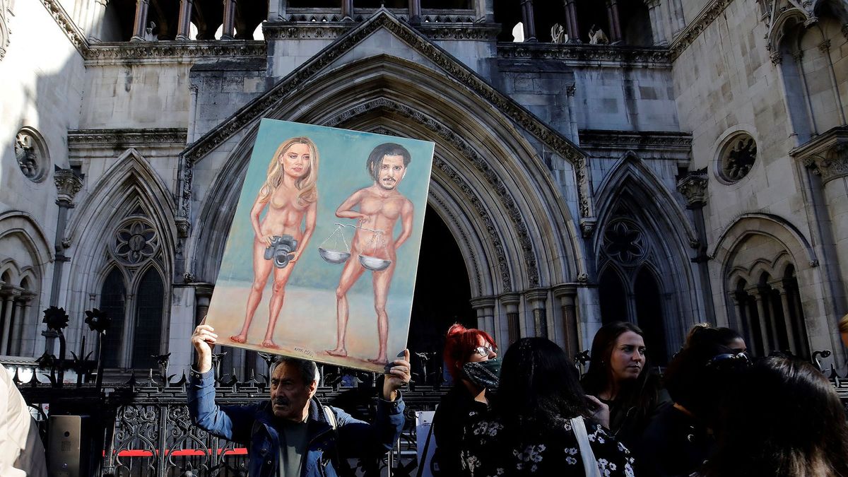 Political satire artist Kaya Mar stands with a painting depicting US actor Johnny Depp and his ex-wife Amber Heard, on the tenth day of Depp's libel trial against News Group Newspapers (NGN), at the High Court in London, on July 20, 2020. - Depp is suing the publishers of The Sun and the author of the article for the claims that called him a "wife-beater" in April 2018. (Photo by Tolga Akmen / AFP)