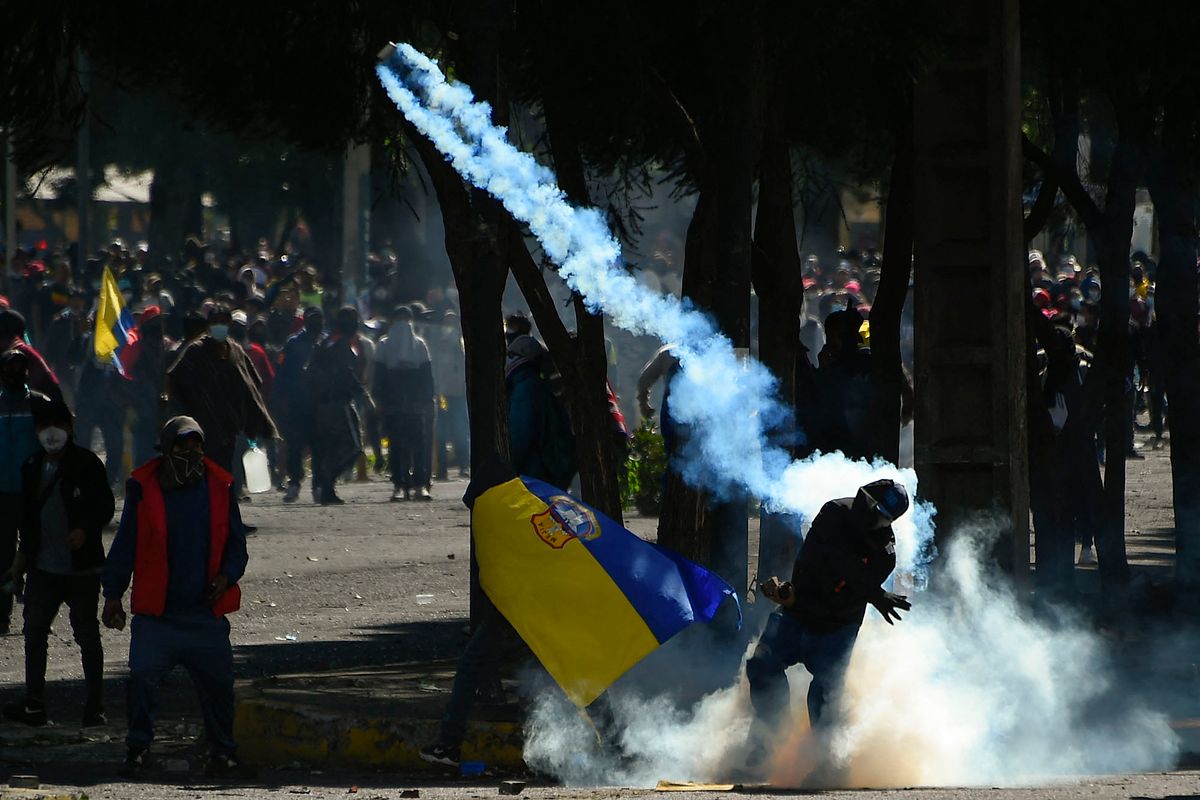 A demonstrator throws a tear gas canister at police officers during clash in the El Arbolito park area in Quito, on June 22, 2022, on the tenth consecutive day of indigenous-led protests against the Ecuadorean government. - Ecuador on Wednesday refused to end its state of emergency and said 18 police officers are "missing" following an attack by indigenous protesters on a police station in the eastern Amazon region. Two people died in clashes with law enforcement during indigenous-led fuel price protests that have triggered regional states of emergency and a curfew in the capital Quito. (Photo by Rodrigo BUENDIA / AFP)