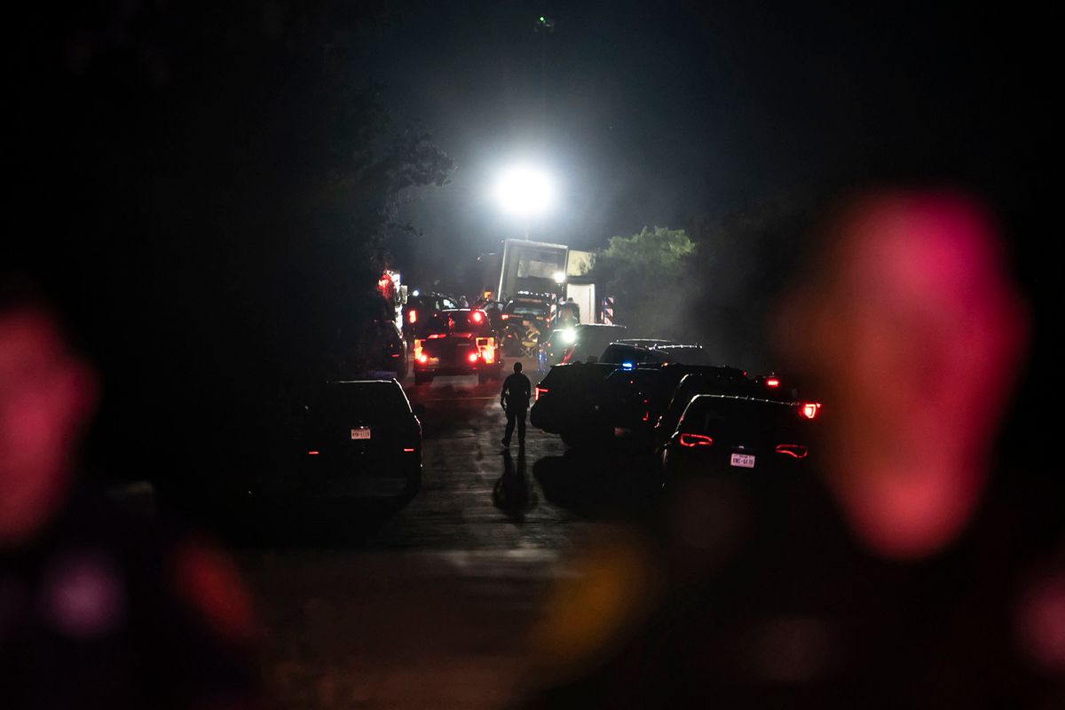 A first responder walks through the scene where a tractor-trailer was discovered with migrants inside outside San Antonio, Texas on June 27, 2022. - At least 46 migrants were found dead June 27, 2022 in and around a tractor-trailer that was abandoned on the roadside on the outskirts of the Texas city of San Antonio. (Photo by Sergio FLORES / AFP)