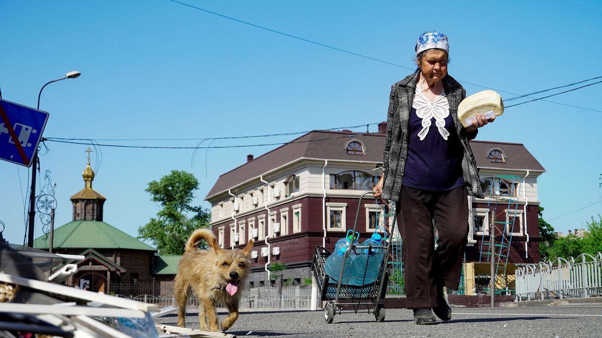 A woman walks with a loaf of bread and bottles of water along a street in Mariupol on June 1, 2022, amid the ongoing Russian military action in Ukraine. (Photo by STRINGER / AFP)