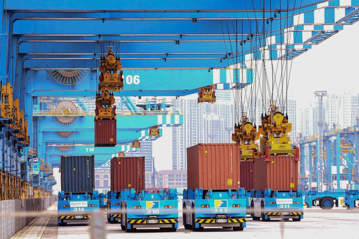 Cranes load containers onto trucks at a port in Qingdao, in China's eastern Shandong province on June 9, 2022. (Photo by AFP) / China OUT