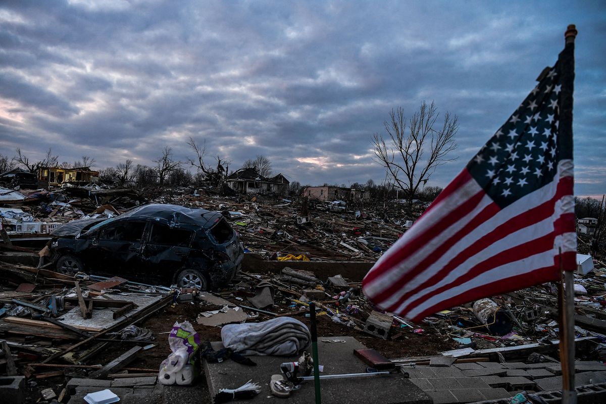 A US national flag waves among debris of a destroyed home in Dawson Springs, Kentucky, on December 14, 2021, four days after tornadoes hit the area. (Photo by CHANDAN KHANNA / AFP)