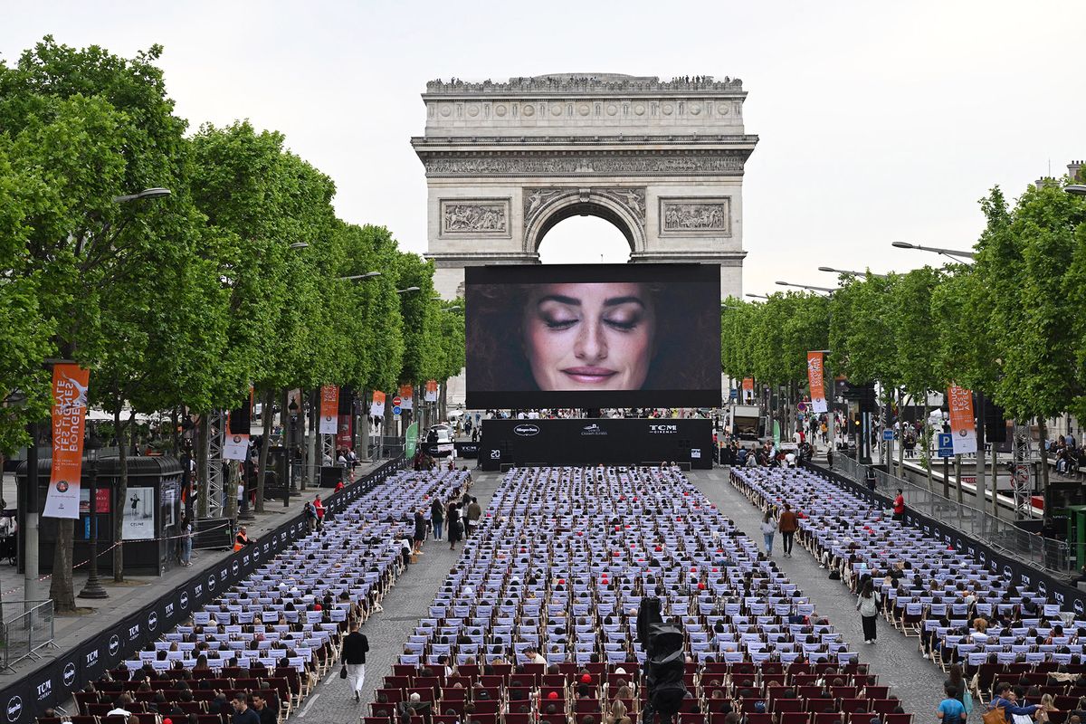 A general view shows members of the public sitting in an open air cinema in front of a giant screen (144 m2) as they attend the third edition of "Sunday in Cinema" (Dimanche au CinÈma) on the Champs-Elysees Avenue in Paris On May 22, 2022. - The movie "A Star is Born", who won an Oscar award in 2018, will be screened for free. (Photo by Emmanuel DUNAND / AFP)