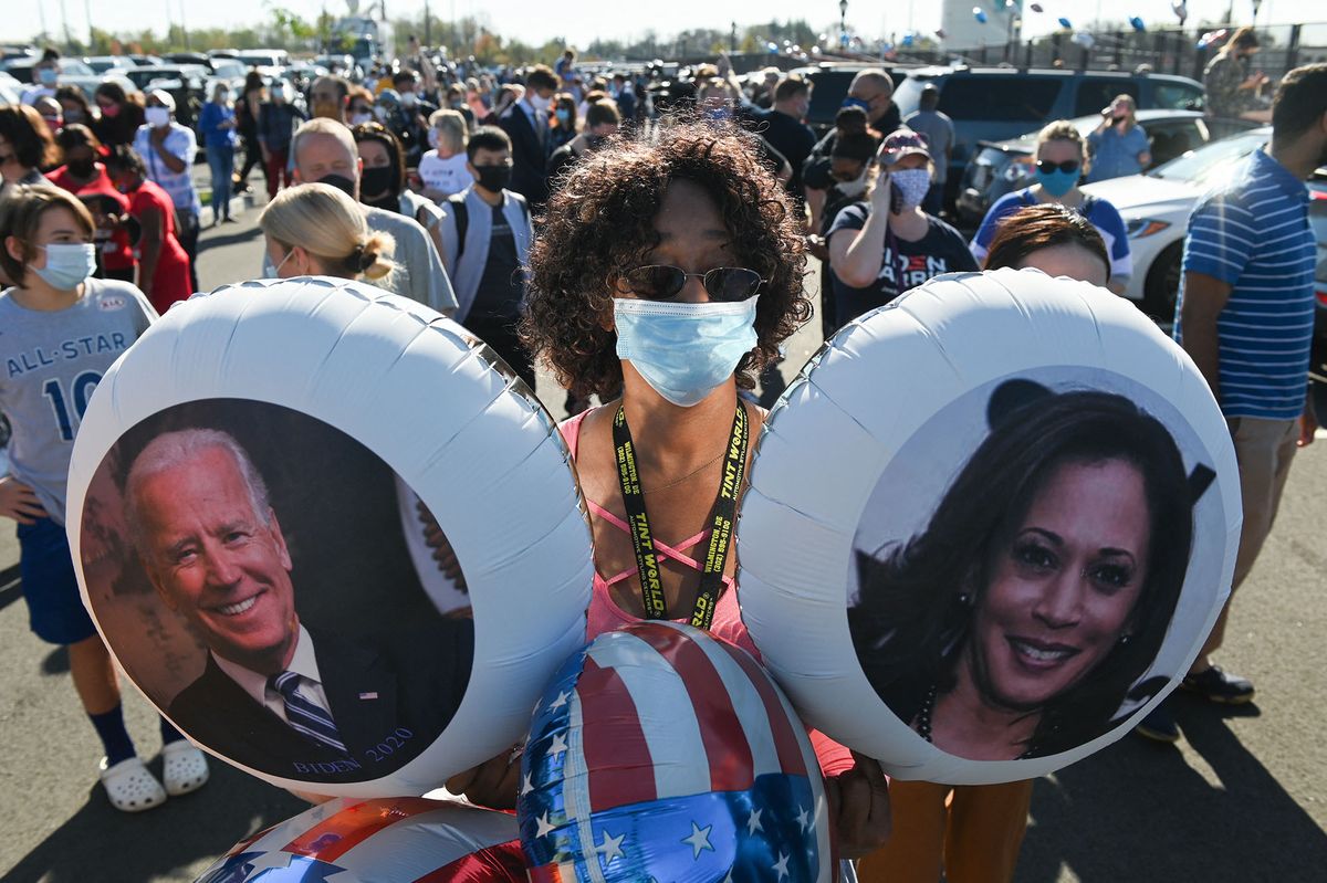 A supporter of president-elect Joe Biden holds balloons with he images of Joe Biden and Kamala Harris as people celebrate his victory in the 2020 presidential election outside the Chase Center in Wilmington, Delaware on November 7, 2020. - Democrat Joe Biden has won the White House, US media said November 7, defeating Donald Trump and ending a presidency that convulsed American politics, shocked the world and left the United States more divided than at any time in decades. (Photo by ROBERTO SCHMIDT / AFP)