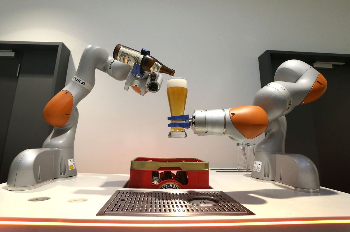 A Kuka robot pours beer into a glass at the 2016 balance sheet press conference of the industrial robot manufacturer held at the Kuka headquarters in Augsburg, Germany, 22 March 2017. Photo: Karl-Josef Hildenbrand/dpa (Photo by KARL-JOSEF HILDENBRAND / DPA / dpa Picture-Alliance via AFP)