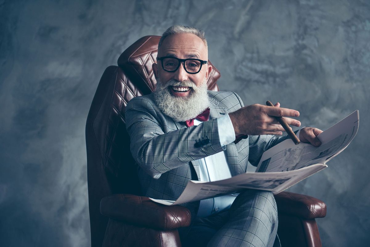gyárigazgatók sokat keresnek Attractive, rich, old, laughing boss with beaming smile in glasses, tux with red bow, have, hold newspaper, smoke cigarette, sitting in leather armchair in workplace over gray background, relax, fun