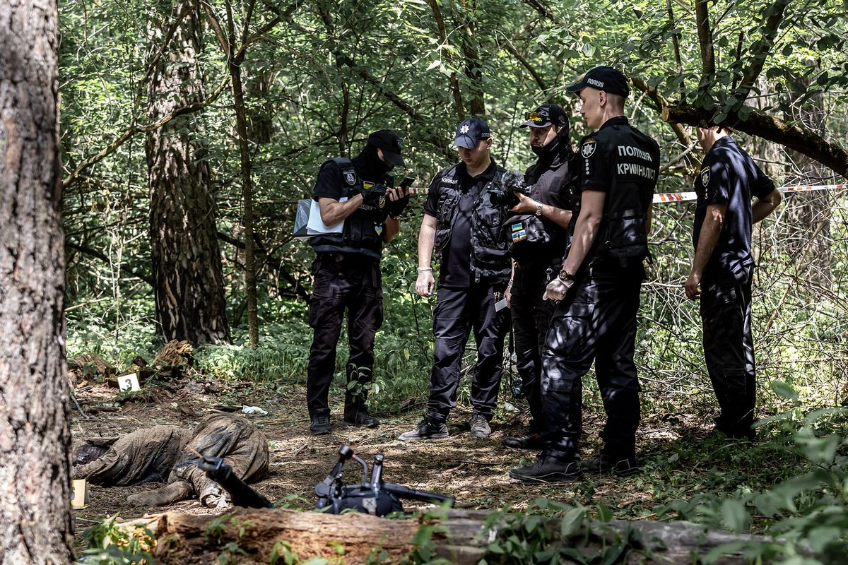 Policemen work in a forest near Bucha, Ukraine during excavation of bodies of Ukrainian civilians murdered by Russian army  - June 13, 2022. The bodies were discovered by a patrol of Territorial Defence Forces and were located near tranches built by the Russian army when it occupied the territory. Seven bodies were excavated from a mass grave. Some of the bodies have signs of being tied and  shot at. An investigation will follow. (Photo by Dominika Zarzycka/NurPhoto) (Photo by Dominika Zarzycka / NurPhoto / NurPhoto via AFP)