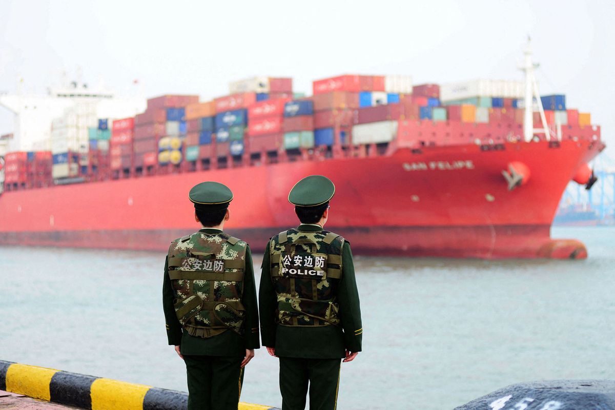 Chinese police officers watch a cargo ship at a port in Qingdao in China's eastern Shandong province on March 8, 2018. - China's trade surplus with the United States narrowed for a second month in a row in February, dropping to 21 billion USD, official data showed on March 8, amid rising trade tensions with the Trump administration. (Photo by AFP) / China OUT