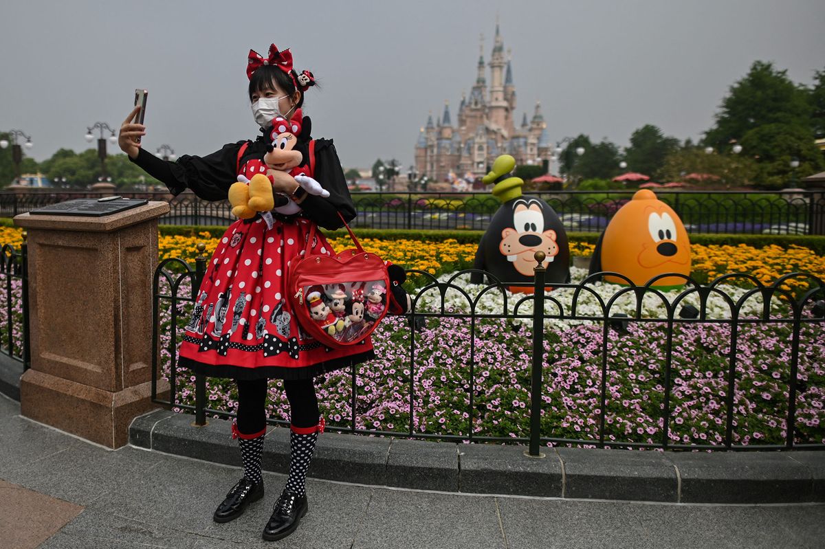 TOPSHOT - A woman wearing a face mask takes a selfie while visiting the Disneyland amusement park in Shanghai on May 11, 2020. - Disneyland Shanghai reopened on May 11 to the public after being closed since January due to the COVID-19 coronavirus outbreak. (Photo by Hector RETAMAL / AFP)