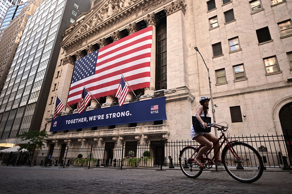 A woman rides past the New York Stock Exchange (NYSE) on July 13, 2020 at Wall Street in New York City. - The Nasdaq tumbled July 13, 2020, ending a three-session streak of records on a weak day for US stocks amid fresh restrictions in California to address the coronavirus. (Photo by Johannes EISELE / AFP)
