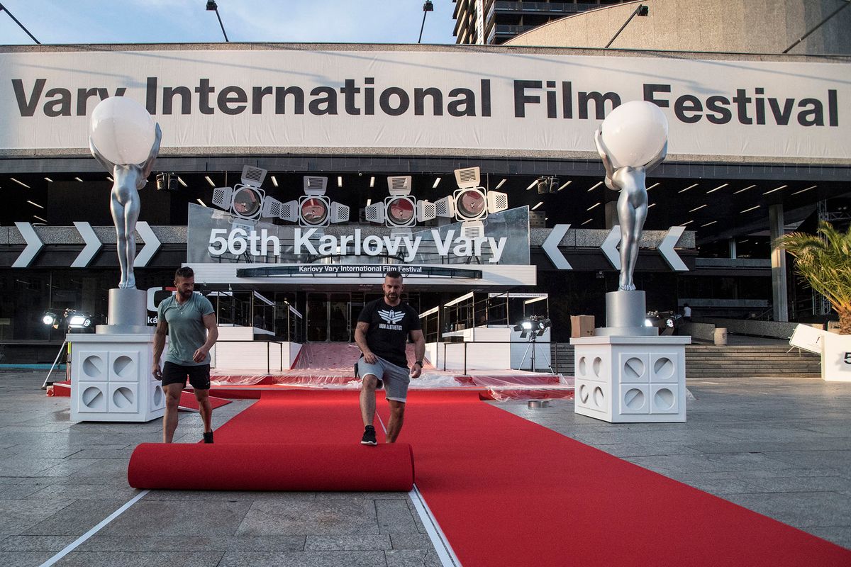 Staff members adjust the red carpet in front of the Thermal movie theater, in preparation for the 56th edition of the Karlovy Vary International Film Festival (KVIFF) in Karlovy Vary, on June 30, 2022. - The 56th KVIFF runs from July 1-9, 2022. (Photo by Michal Cizek / AFP)