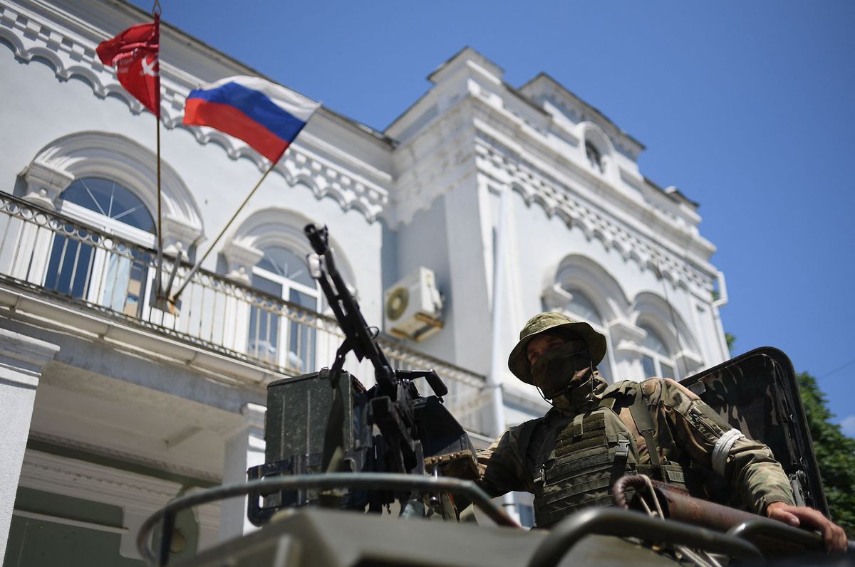 8214944 13.06.2022 A Russian serviceman drives past Berdyansk Hotel with the Russian flag and the flag of the non-existent USSR on the facade in Berdyansk, Zaporizhzhia region, partially controlled by pro-Russian troops, Ukraine. Alexey Maishev / Sputnik (Photo by Alexey Maishev / Sputnik / Sputnik via AFP)