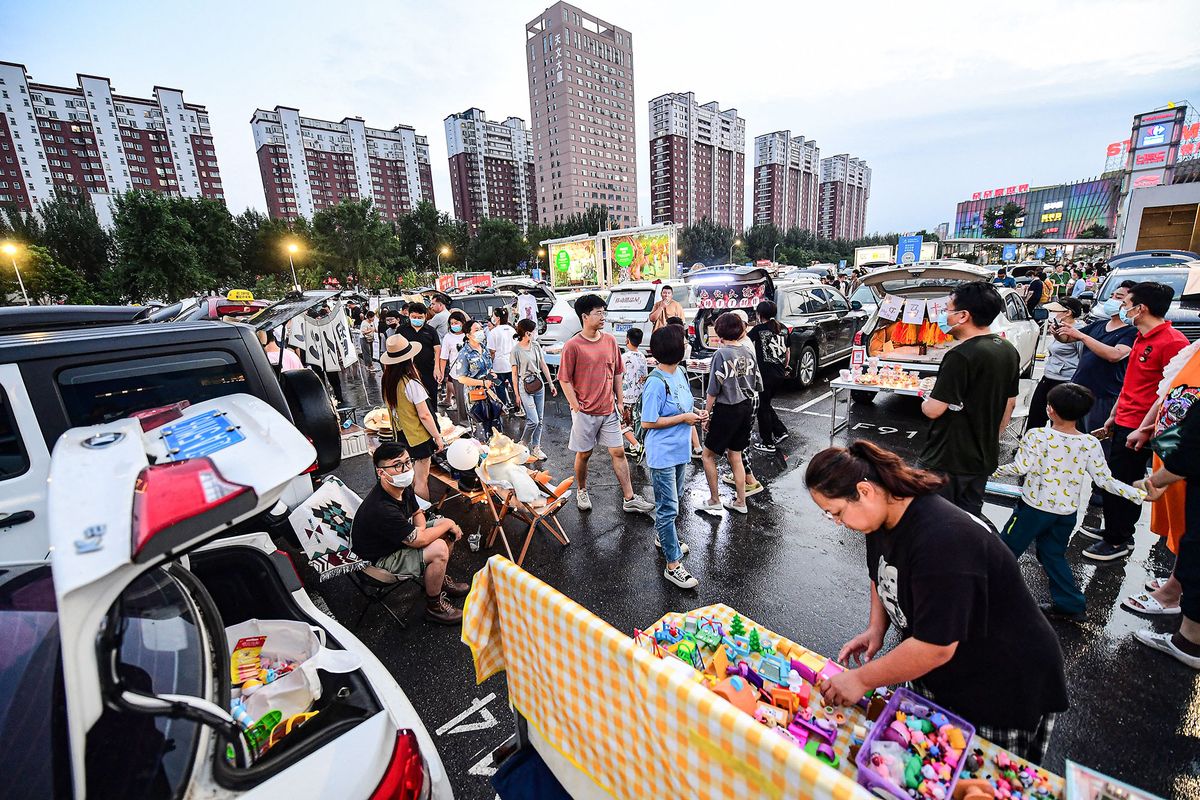 This photo taken on July 2, 2022 shows people selling items from the trunks of their cars at a market located in a parking lot in Shenyang, in China's northeastern Liaoning province. (Photo by AFP) / China OUT