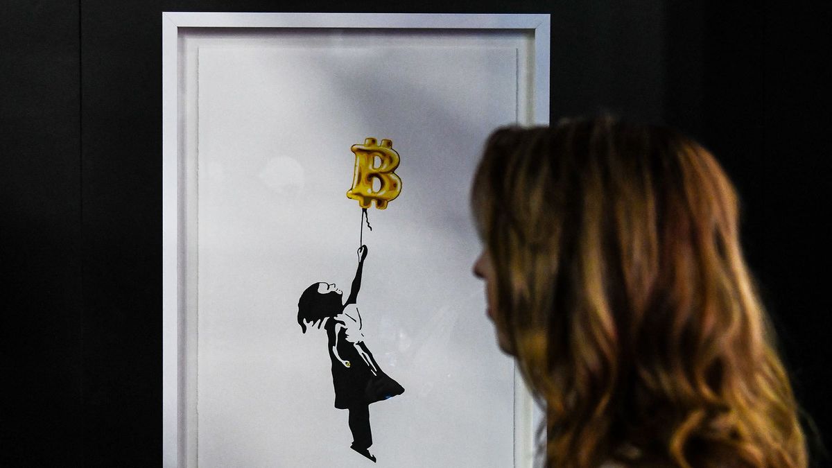 A woman looks at Bitcoin themed piece of art during the Bitcoin 2022 Conference at the Miami Beach Convention Center in Miami Beach, Florida, on April 7, 2022. - The Bitcoin 2022 Conference is a four day event from April 6-9, with over 30,000 people expected to attend in-person and over 7 million live stream viewers worldwide. (Photo by CHANDAN KHANNA / AFP)
