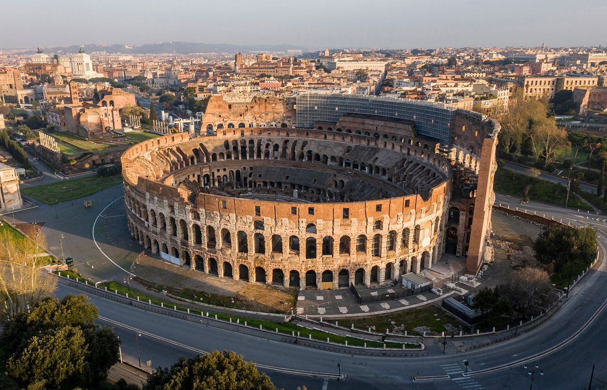 A morning aerial photo taken on March 30, 2020 shows deserted streets and the Colosseum monument in Rome during the country's lockdown aimed at curbing the spread of the COVID-19 infection, caused by the novel coronavirus. (Photo by Elio CASTORIA / AFP) / Italy OUT