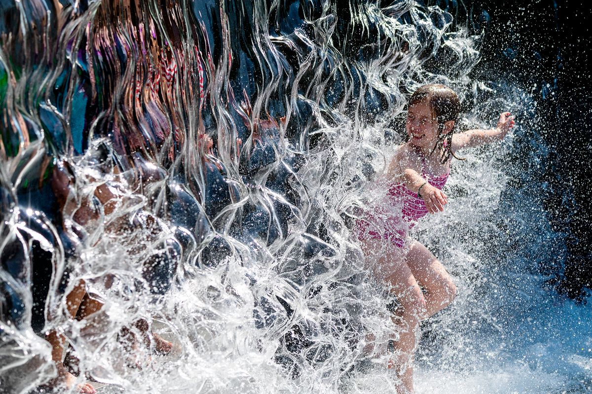 A young girl splashes through a waterfall at a park in Washington, DC, on June 28, 2021, as a heatwave moves over much of the United States. - Swathes of the United States and Canada endured record-setting heat on June 27, 2021, forcing schools and Covid-19 testing centers to close and the postponement of an Olympic athletics qualifying event, with forecasters warning of worse to come. The village of Lytton in British Columbia broke the record for Canada's all-time high, with a temperature of 46.6 degrees Celsius (116 Fahrenheit), said Environment Canada. (Photo by JIM WATSON / AFP)