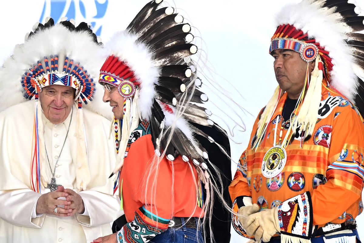 Pope Francis wears a headdress presented to him by Indigenous leaders at Muskwa Park in Maskwacis, Alberta, Canada, on July 25, 2022. - Pope Francis will make a historic personal apology Monday to Indigenous survivors of child abuse committed over decades at Catholic-run institutions in Canada, at the start of a week-long visit he has described as a "penitential journey." (Photo by Patrick T. FALLON / AFP)