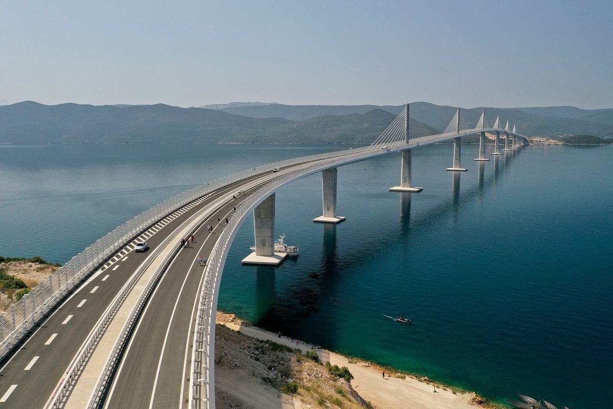 Komarna, 2022. július 26.Légi felvétel a Peljesac hídról a horvátországi Komarna közelében 2022. július 26-án, az átadás napján. A 420 millió eurós költséggel a kínai China Road and Bridge Corporation (CRBC) által megépített híd a szárazföld és a Peljesac-félsziget között ível át 55 méter magasságban a tengeröböl fölött, és így megteremti az összeköttetést Bosznia-Hercegovina tengerpartjának elkerülésével az attól északra és délre húzódó, Horvátországhoz tartozó Adria-parti területek között.MTI/AP