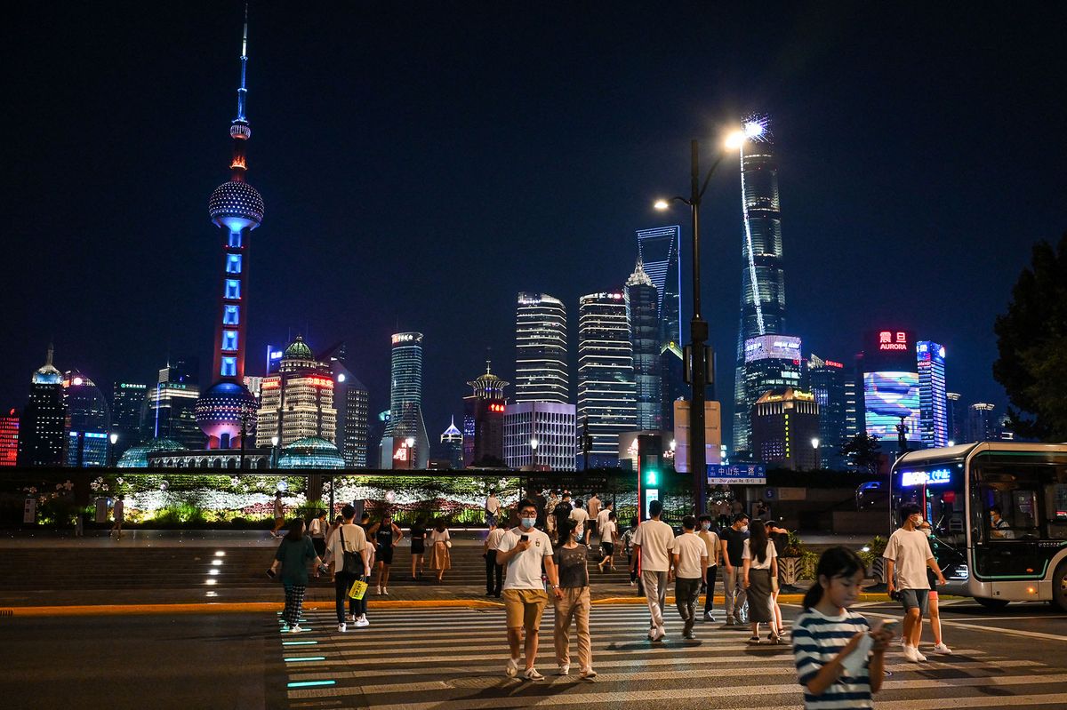 People walk on The Bund in the Huangpu district of Shanghai on July 12, 2022. (Photo by Hector RETAMAL / AFP)