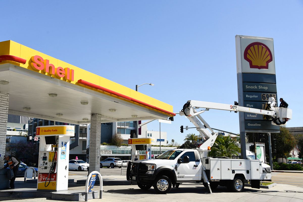 An electrical contractor repairs a sign with gasoline fuel prices above six and seven dollars a gallon at the Shell gas station at Fairfax and Olympic Blvd in Los Angeles, California, on March 8, 2022. (Photo by Patrick T. FALLON / AFP)