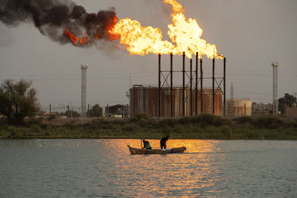 Iraqi men sail in the Shatt al-Arab river across from the Nahr Bin Omar oilfield in Iraq's southern province of Basra on July 18, 2022. (Photo by Hussein Faleh / AFP)