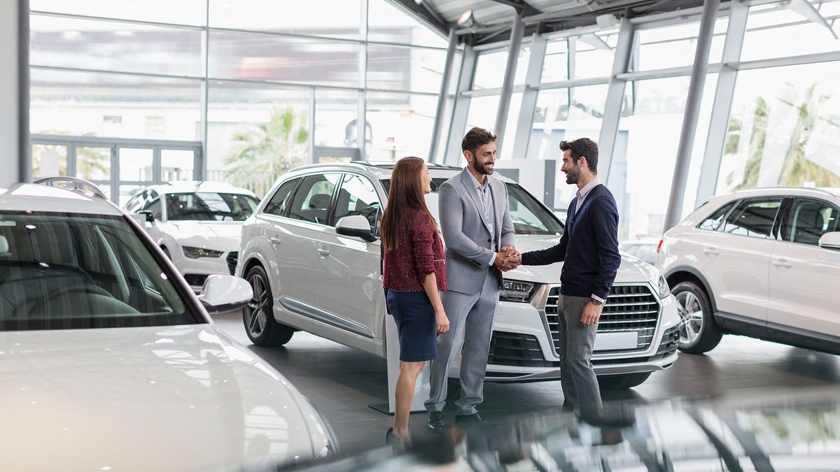 Car salesman and customers handshaking in car dealership showroom. (Photo by CAIA IMAGE/SCIENCE PHOTO LIBRARY / NEW / Science Photo Library via AFP)