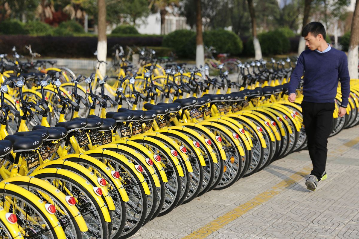 --FILE--A student walks past bicycles of Chinese bike-sharing services ofo in a college campus in Anqing city, east China's Anhui province, 6 December 2016.China's bike-sharing startup ofo announced on Wednesday that it has completed D-round financing of 3.1 billion yuan ($450 million), led by global investment institution Digital Sky Technology, or DST. Other investors include ride-hailing service provider Didi Chuxing, private equity fund CITIC Private Equity Funds Management Co Ltd and investment institution Matrix Partners China. The financing, the largest of a single deal in the bike-sharing industry, has made ofo the most valued unicorn company among its peers. (Photo by Xie cheng / Imaginechina / Imaginechina via AFP)