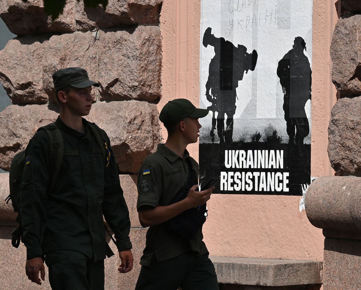 Ukrainian soldiers walk past a poster on Ukraine resistance" in Kyiv city centre on July 7, 2022. (Photo by Sergei SUPINSKY / AFP)