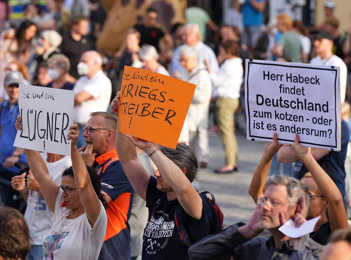 28 July 2022, Bavaria, Bayreuth: Demonstrators hold placards reading "Liar," "You're a warmonger," and "Mr. Habeck thinks Germany sucks - or is it the other way around?" behind a barrier in the city's Court of Honor during the Citizens' Dialogue hosted by Federal Economics Minister Habeck. There were also loud whistles and boos, many citizens shouted at Habeck: "Get lost". Photo: Soeren Stache/dpa (Photo by SOEREN STACHE / DPA / dpa Picture-Alliance via AFP)