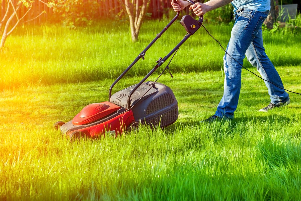 Man,In,Motion,With,Lawnmower,And,Mows,Green,Grass