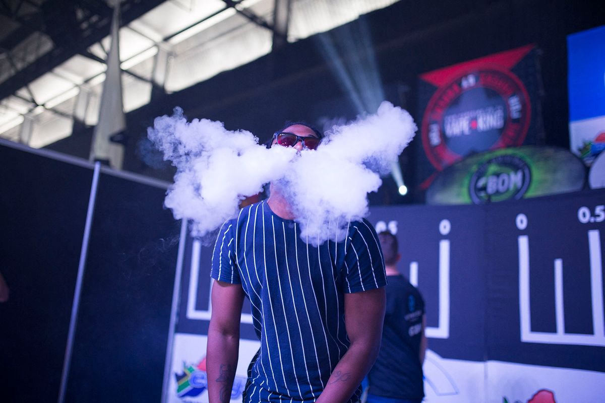 A man blows smoke from an electronic cigarette as he takes part in a vaping trick competition during VapeCon in Pretoria on September 1, 2019. - VapeCon is South Africa's largest convention dedicated to electronic cigarettes and vaping. (Photo by GUILLEM SARTORIO / AFP)