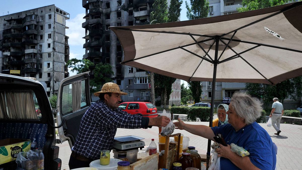 People wander at a makeshift market in the town of Borodianka, near Kyiv on July 7, 2022. (Photo by Sergei CHUZAVKOV / AFP)