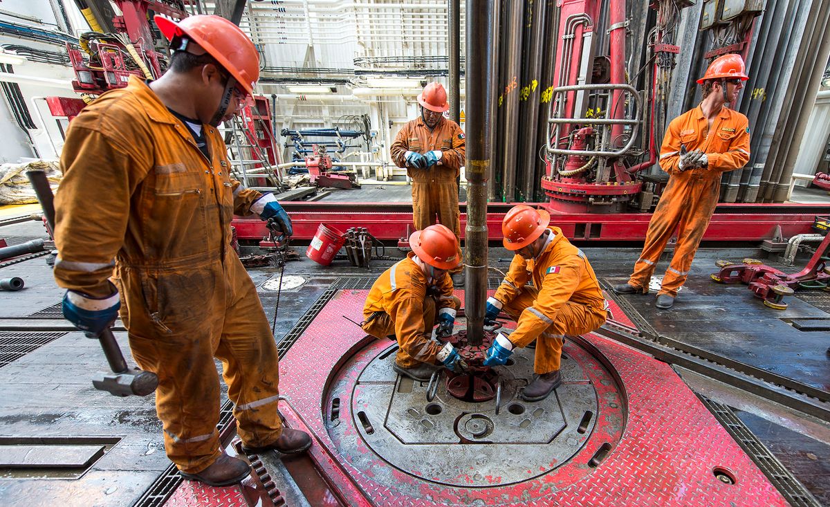 Derrick hands remove the drilling tool with a sample of the marine seabed at La Muralla IV exploration oil rig, operated by Mexican company "Grupo R" and working for Mexico's state-owned oil company  PEMEX, in the Gulf of Mexico on August 30, 2013. The semisubmersible platform is able to drill to a depth of 10.000 meters in an enviroment such as the Gulf of Mexico.    AFP PHOTO/OMAR TORRES (Photo by Omar TORRES / AFP)