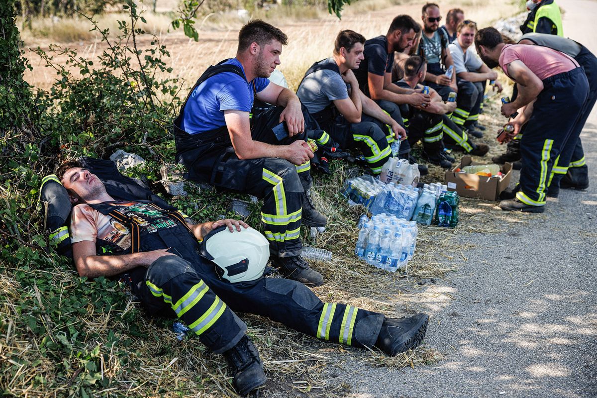 TEMNICA, SLOVENIA - 2022/07/22: Exhausted firemen rest after containing a part of a large wildfire that burns near the village of Temnica in the Karst region of Slovenia for the sixth day. About a thousand firemen with air support from three Slovenian helicopters, two Serbian helicopters, an Austrian helicopter, a Slovakian Black Hawk helicopter and two Hungarian helicopters, a Croatian Canadair firefighting airplane and a Slovenian army Pilatus airplane continued battling a large wildfire that broke out five days ago and has intensified in the Karst region of Slovenia. Villages in the area were evacuated. This is the largest wildfire in the history of Slovenia. (Photo by Luka Dakskobler/SOPA Images/LightRocket via Getty Images)
