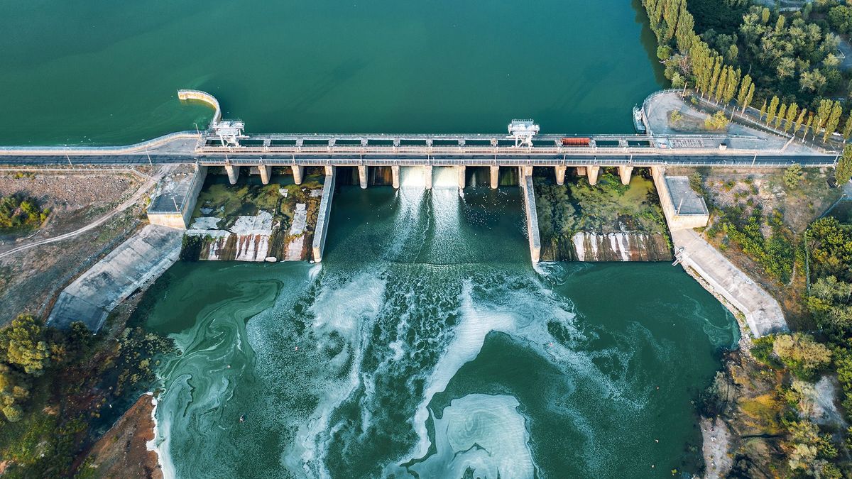 Aerial,Panoramic,View,Of,Concrete,Dam,At,Reservoir,With,Flowing, Aerial panoramic view of concrete Dam at reservoir with flowing water, hydroelectricity power station, drone shot.