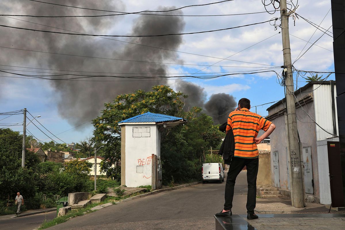 Odessza, 2022. július 16.Férfi telefonál, miközben füst száll fel a fekete-tengeri kikötőváros, Odessza felett egy orosz tüzérségi támadást követően 2022. július 16-án.MTI/AP/Nina Lyashonok