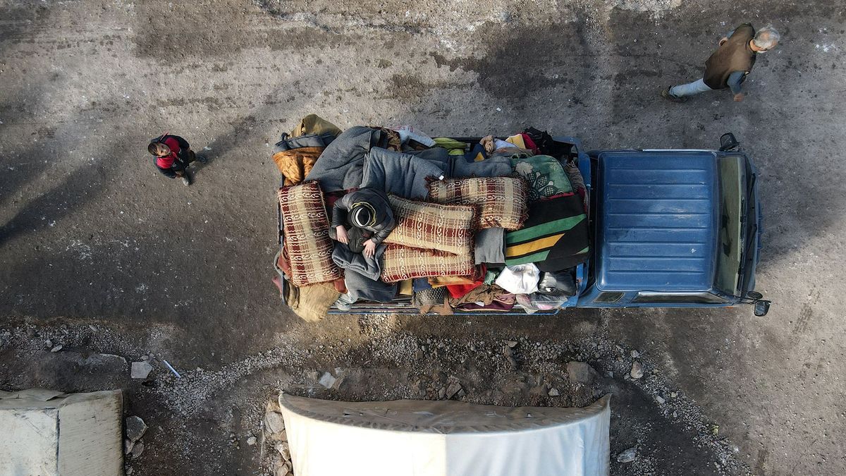 This aerial view shows internally displaced Syrians loading their belongings onto a truck at a camp, before being transported to a new housing complex in the opposition-held area of Bizaah, east of the city of al-Bab in the northern Aleppo governorate, built with the support of Turkey's emergencies agency AFAD, on February 9, 2022. - A housing complex built for displaced Syrians near the Turkish-held Syrian city of Al-Bab is the latest in a series of residential projects sponsored by Ankara. Turkey's goal is to create a so-called "safe zone" along its border to keep Syrians displaced by war from crossing into its territory, and to allow it to send back some of the millions who already did. (Photo by Bakr ALKASEM / AFP)