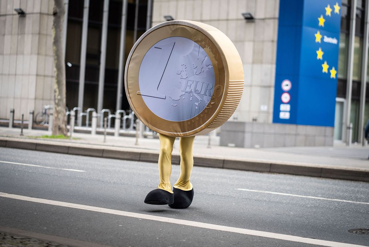 21 February 2022, Hessen, Frankfurt/Main: A performer dressed as a "Eurolino" in the form of a one-euro coin on legs crosses a street in front of the temporary headquarters of the Deutsche Bundesbank in Frankfurt during filming. Since the actual headquarters is currently being renovated and remodeled, the Bundesbank staff and their offices are relocated to a building in the city center. The Eurolino is involved in internal filming to communicate the new locations and procedures. Photo: Frank Rumpenhorst/dpa (Photo by FRANK RUMPENHORST / DPA / dpa Picture-Alliance via AFP)
