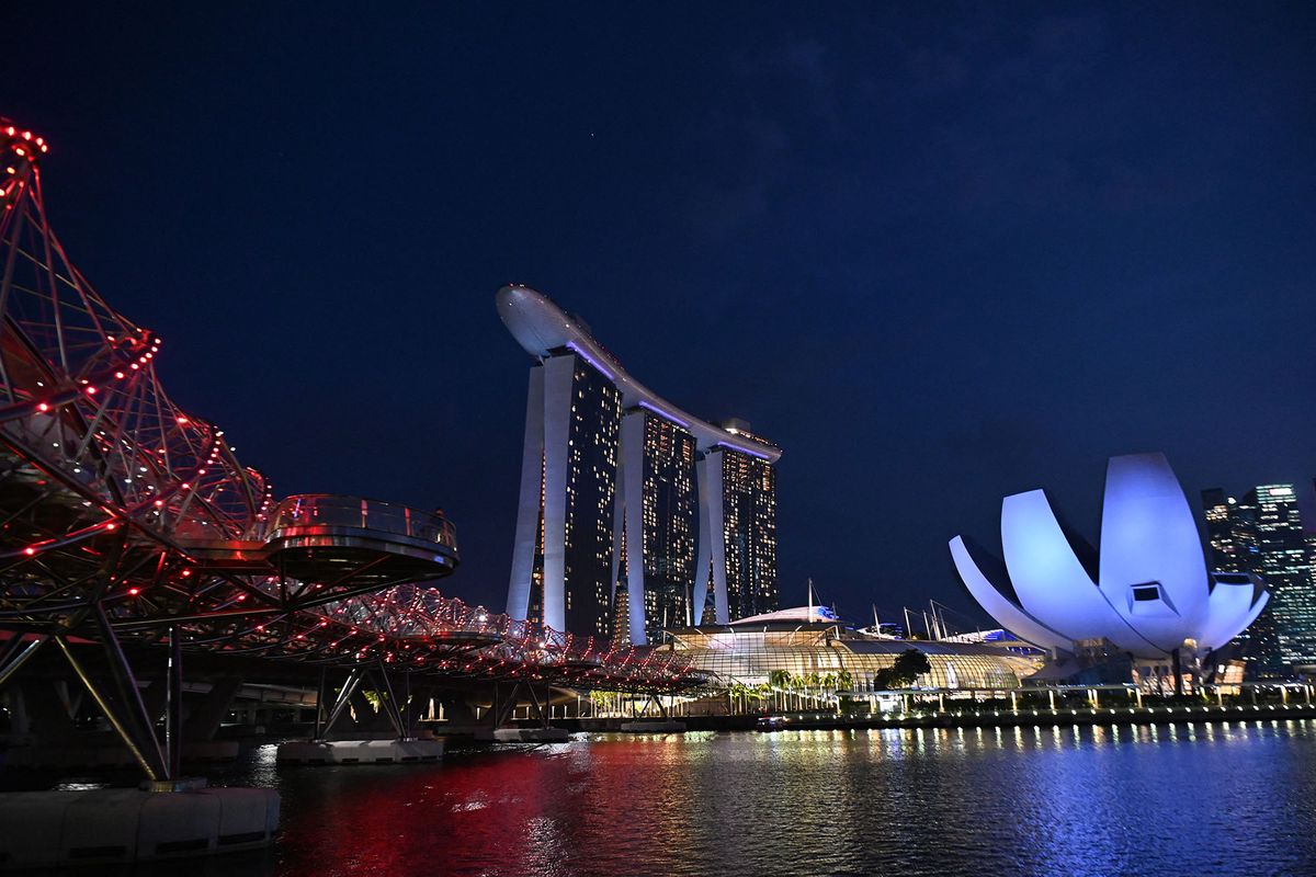 The Marina Bay Sands hotel and resorts (C) and the ArtScience Museum (R) are illuminated under the evening sky in Singapore on March 8, 2019. (Photo by ROSLAN RAHMAN / AFP)