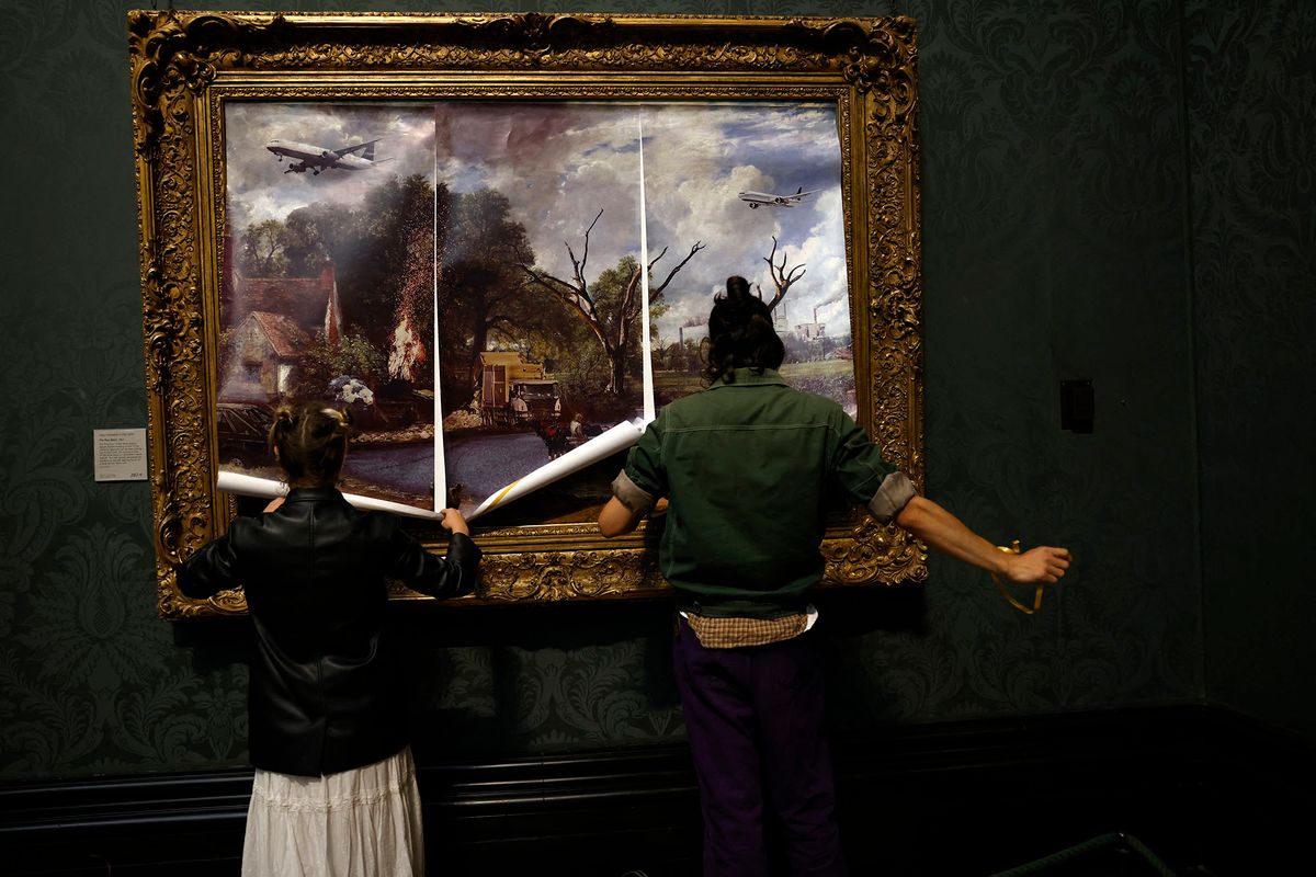 Activists from the 'Just Stop Oil' campaign group cover 'The Hay Wain' painting by English artist John Constable, in a mock 'undated' version including roads and aircraft, before glueing their hands to the frame in protest against the use of fossil fuels, in the National Gallery in London on July 4, 2022. (Photo by CARLOS JASSO / AFP)