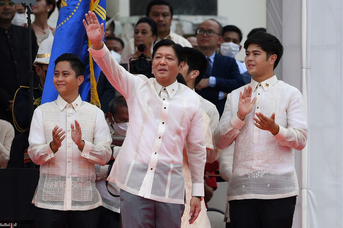 New Philippine President Ferdinand Marcos Jr. (C) waves to supporters as his sons look on after being sworn in as the country's new leader, during the inauguration ceremony at the National Museum in Manila on June 30, 2022. (Photo by Ted ALJIBE / AFP)