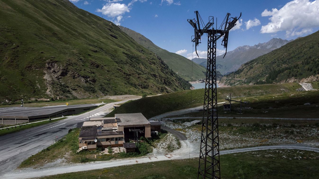 A picture taken on June 20, 2022, above Bourg-Saint-Pierre shows a rusty gondola mast in front of the ruins of a building that once housed a restaurant, a ski-rental shop and the gondola lift departure station of the Super Saint-Bernard ski resort above Bourg-Saint-Pierre. - The lifts at the once bustling Super Saint-Bernard ski resort in Switzerland's southern Wallis canton, near the Italian border, have not run since 2010. In all, up to two million Swiss francs ($2.1 million) will be needed to dismantle the station. In recent years, shortages of snow and especially of money have seen many of Switzerland's smaller, local stations struggle to keep their lifts running. (Photo by Fabrice COFFRINI / AFP)