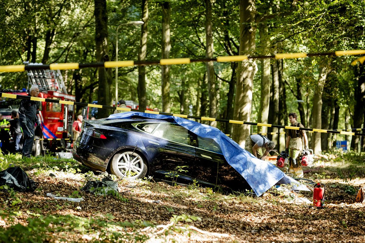 Rescue workers proceed with caution around the spot where a Tesla slammed into a tree in Baarn, on September 7, 2016. - Pioneering US electric car firm Tesla said on September 8, it was investigating a fatal crash in The Netherlands when a Model S sedan ploughed at high-speed into a tree. (Photo by Robin van Lonkhuijsen / ANP / AFP) / Netherlands OUT