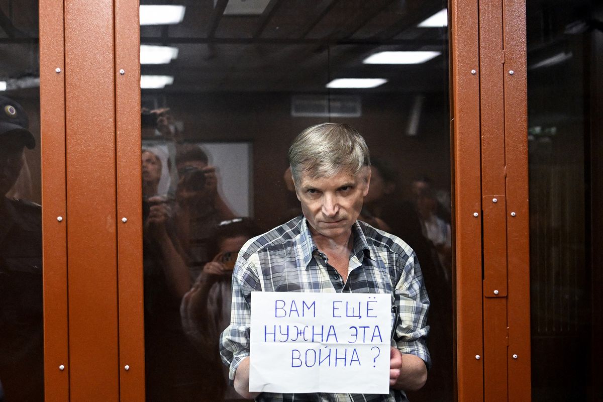 Moscow city deputy Alexei Gorinov, accused of spreading "knowingly false information" about the Russian army fighting in Ukraine, stands with a poster reading ""Do you still need this war?" inside a glass cell during the vedict hearing in his trial at a courthouse in Moscow on July 8, 2022. (Photo by Kirill KUDRYAVTSEV / AFP)